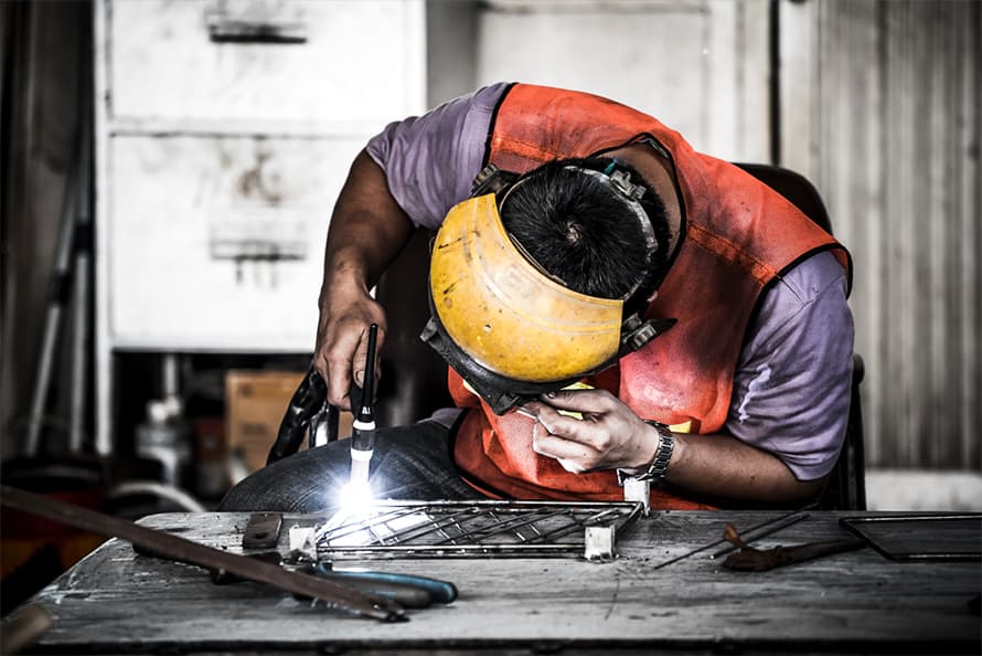 Man TIG Welding in a shop.